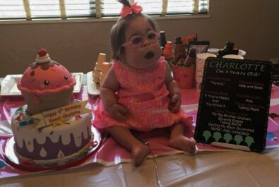 girl next to a charlotte card and a cupcake cake