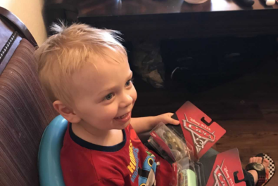 boy sitting with two cars toys