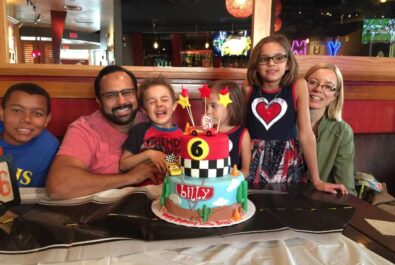 family at a restaurant with a cars cake