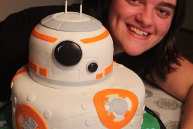 kid next to a star wars cake