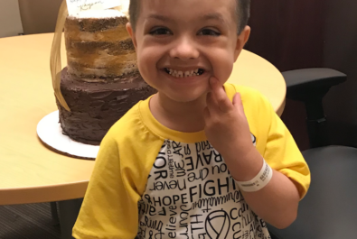 boy smiling with a cake behind him