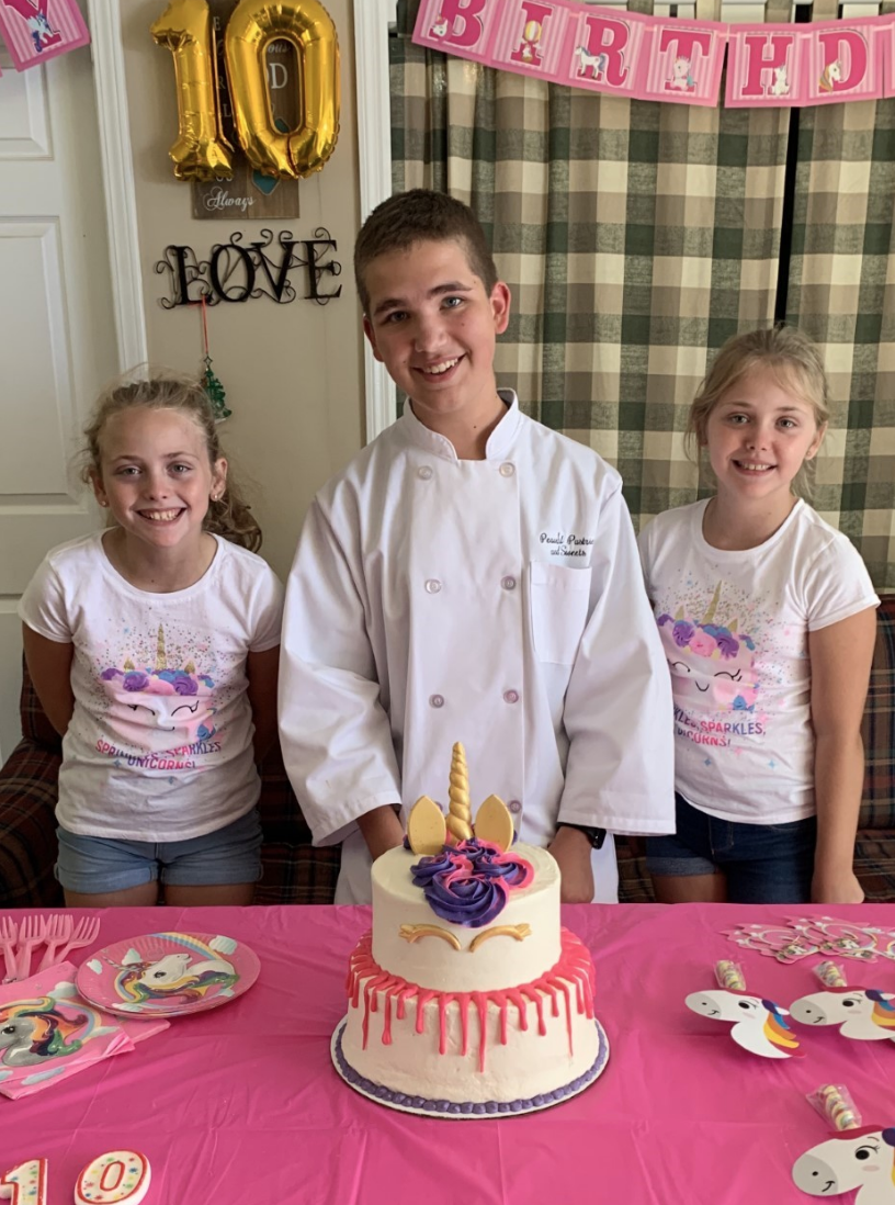 chef with two girls next to a unicorn cake