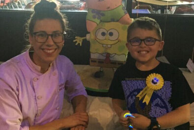 kid and woman in front of a spongebob cake