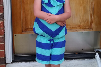 young girl in stripes in front of a door